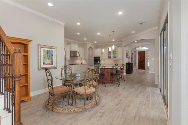 This photo showcases a bright, open concept living space featuring a modern kitchen with an island, pendant lighting, and stainless-steel appliances. There's a cozy dining area that will fit any size table table and designed to for entertaining. Wood-like flooring and neutral tones enhance the inviting atmosphere. | Image 20