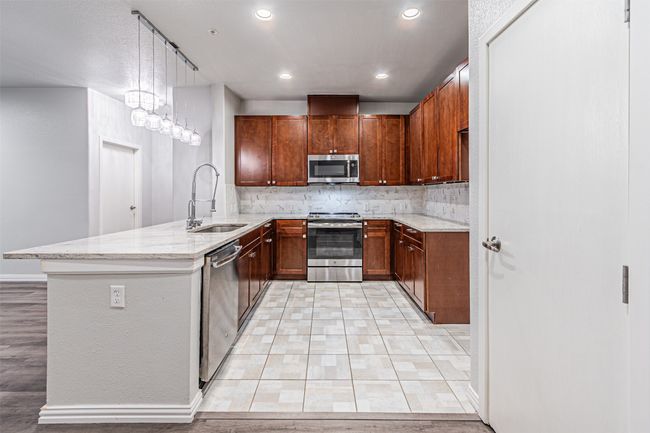 Kitchen featuring appliances with stainless steel finishes, light stone countertops, a peninsula, tasteful backsplash, and recessed lighting | Image 21