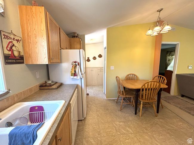 Kitchen with a chandelier, decorative light fixtures, freestanding refrigerator, vaulted ceiling, and a sink | Image 45