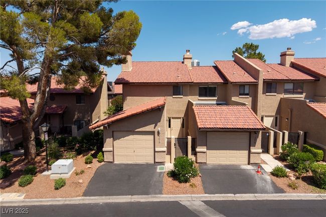 View of front of home with driveway, a tile roof, stucco siding, a garage, and a residential view | Image 21