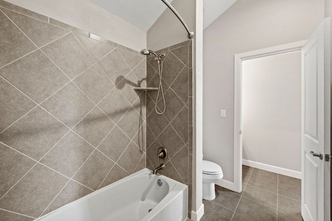 Bathroom featuring toilet, shower / bathtub combination, tile patterned flooring, and baseboards | Image 29