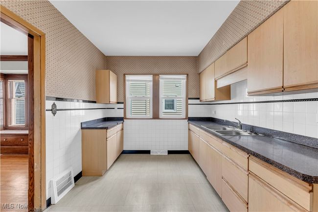 Kitchen with dark countertops, visible vents, light brown cabinets, and a sink | Image 11