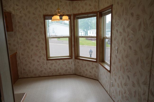 Unfurnished dining area with wallpapered walls, a chandelier, and light floors | Image 9