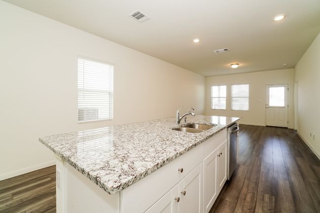 Kitchen with dishwasher, dark wood-style floors, white cabinets, an island with sink, and recessed lighting | Image 11