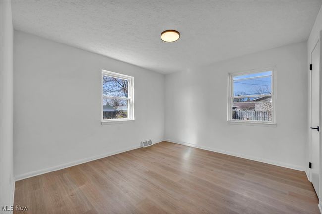 Empty room with a textured ceiling, wood finished floors, baseboards, and visible vents | Image 15
