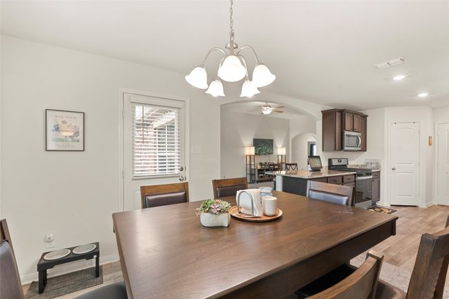 Dining space with light LVP flooring, arched walkways, ceiling fan with notable chandelier, and baseboards | Image 13