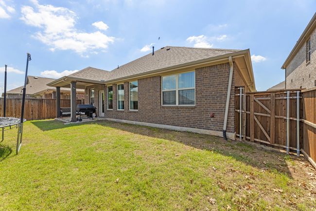 Rear view of property featuring a trampoline, a fenced backyard, and brick siding | Image 37