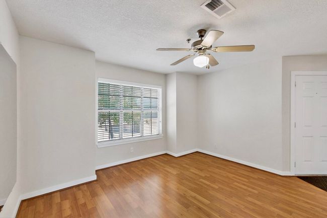 Spare room featuring a textured ceiling, light wood-style floors, and a ceiling fan | Image 8