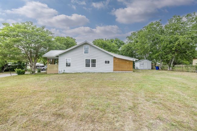 Back of property featuring a shed, metal roof, a lawn, fence, and an outbuilding | Image 36