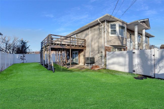 Rear view of property featuring a wooden deck, a yard, and central AC unit | Image 4