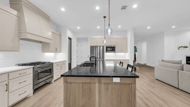 Kitchen with appliances with stainless steel finishes, a sink, light wood-style floors, open floor plan, and tasteful backsplash | Image 20