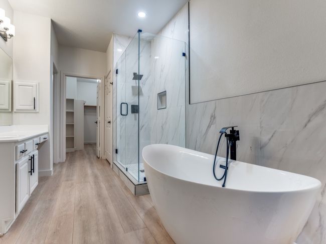 Full bath featuring vanity, a marble finish shower, a freestanding tub, wood finished floors, and tile walls | Image 17