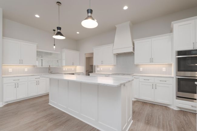 Kitchen with premium range hood, stainless steel double oven, a center island, and light wood-type flooring | Image 10