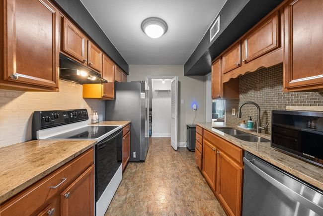 Kitchen with Quartz Countertops, Stainless Steel Refrigerator with ice dispenser, electric range and decorative backsplash | Image 8