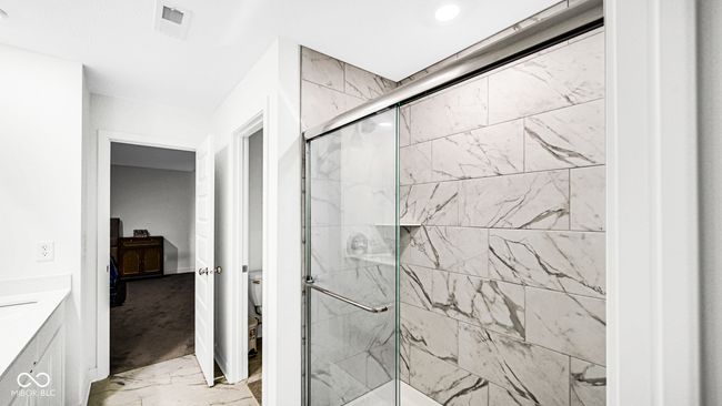 full bath featuring marble finish floors, a stall shower, toilet, and vanity | Image 33