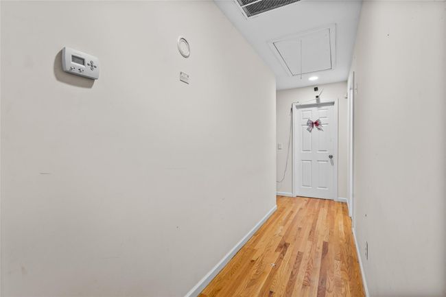 Hallway featuring light wood finished floors, visible vents, baseboards, and attic access | Image 40
