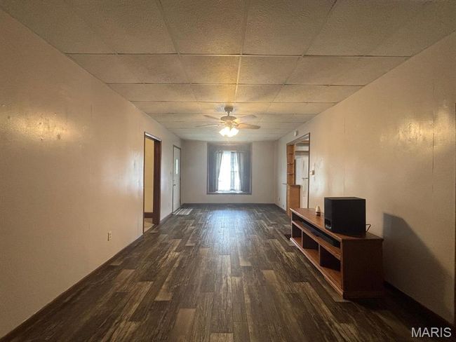 Unfurnished living room with dark wood-type flooring, a paneled ceiling, and ceiling fan | Image 17