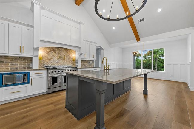 Kitchen featuring wood-type flooring, range with two ovens, built in microwave, backsplash, and beam ceiling | Image 13