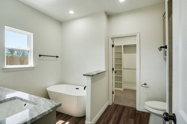 Full bath with wood finished floors, a walk in closet, a freestanding tub, toilet, and recessed lighting | Image 16