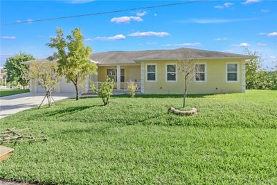 Elevated, one story home with tiled front porch, double front doors, front lawn and XL garage | Image 3