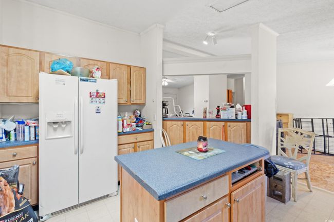 Kitchen featuring white fridge with ice dispenser, light brown cabinets, a center island, light floors, and ornamental molding | Image 8
