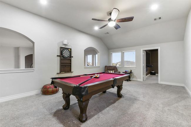 The large game room easily accommodates a pool table with plenty of extra space for a seating area, making it perfect for both games and relaxation. A door leads into the media room, providing a seamless transition between entertainment spaces. This setup is ideal for hosting friends and family or enjoying a movie night in style. | Image 25