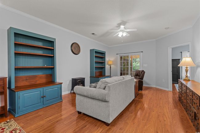 Living room with ceiling fan, light wood-style flooring, ornamental molding, a wood stove, and baseboards | Image 17