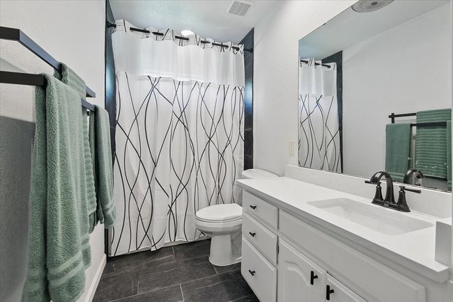 Bathroom with vanity, toilet, curtained shower, and tile patterned floors | Image 21