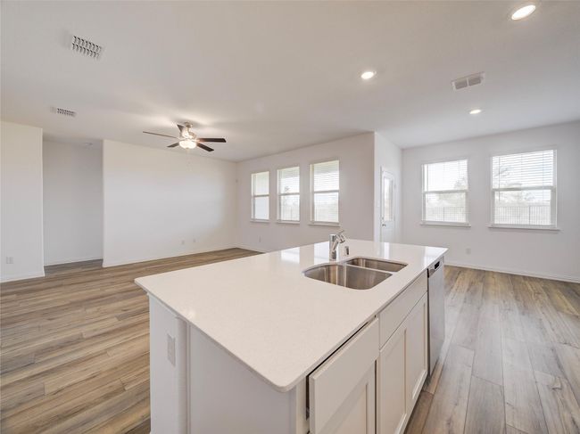 Kitchen with a sink, open floor plan, stainless steel dishwasher, a center island with sink, and light countertops | Image 7