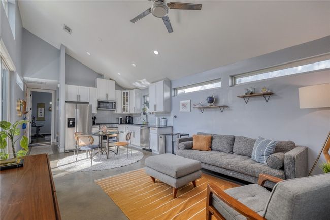 Living area with finished concrete flooring, high vaulted ceiling, ceiling fan, and recessed lighting | Image 5
