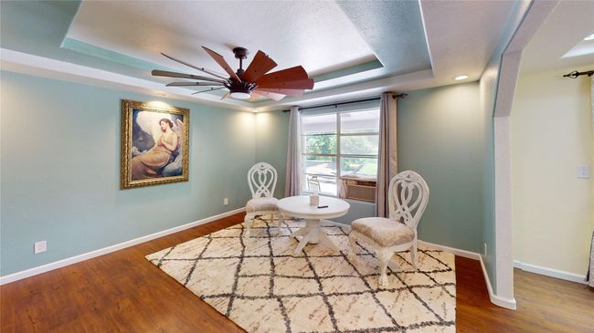Sitting room with dark wood-type flooring, ceiling fan, a tray ceiling, and a textured ceiling | Image 4