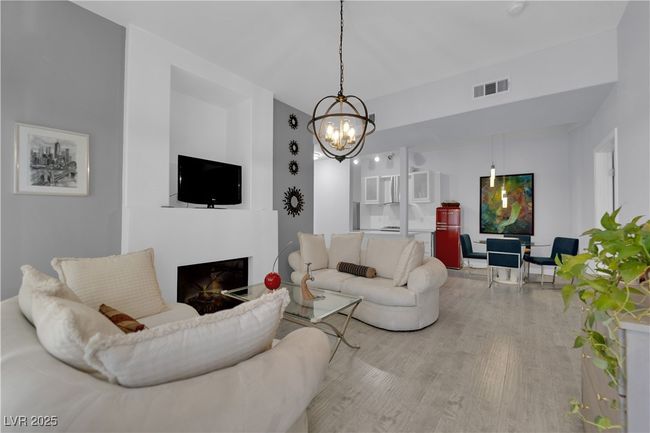 Living area with wood finished floors, a chandelier, and a fireplace | Image 5