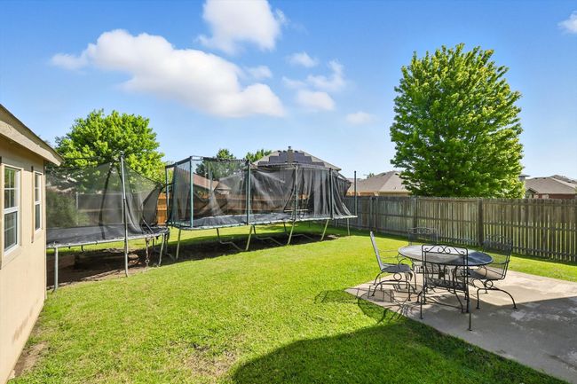 Fenced backyard featuring a trampoline and a patio | Image 17