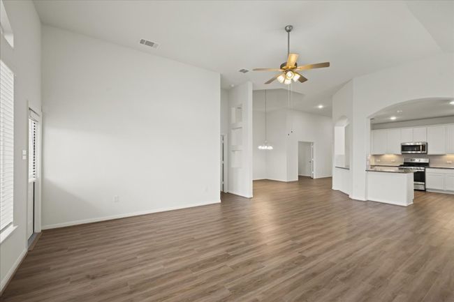 Unfurnished living room with a ceiling fan, wood finished floors, recessed lighting, a chandelier, and baseboards | Image 8