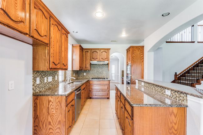 Kitchen featuring arched walkways, under cabinet range hood, appliances with stainless steel finishes, brown cabinets, and recessed lighting | Image 10