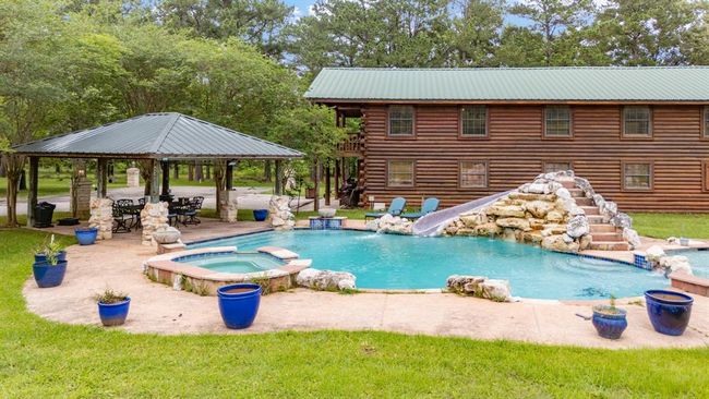 Discover a gorgeous guest/apartment 3 Bedroom/2 Baths with barn below, 4 Stables, Laundry Room, Workout Area and Storage set in a serene wooded area. Enjoy the stunning pool with a rock waterfall and slide and unwind in the nearby hot tub. A covered outdoor seating area is perfect for relaxation and entertaining. | Image 9