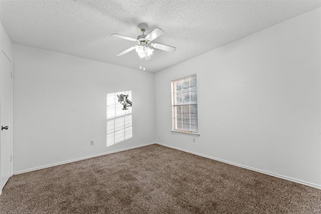 Empty room with carpet floors, a ceiling fan, a textured ceiling, and baseboards | Image 27