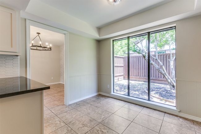 Empty room featuring a chandelier, light tile patterned floors, a wainscoted wall, a raised ceiling, and a decorative wall | Image 25
