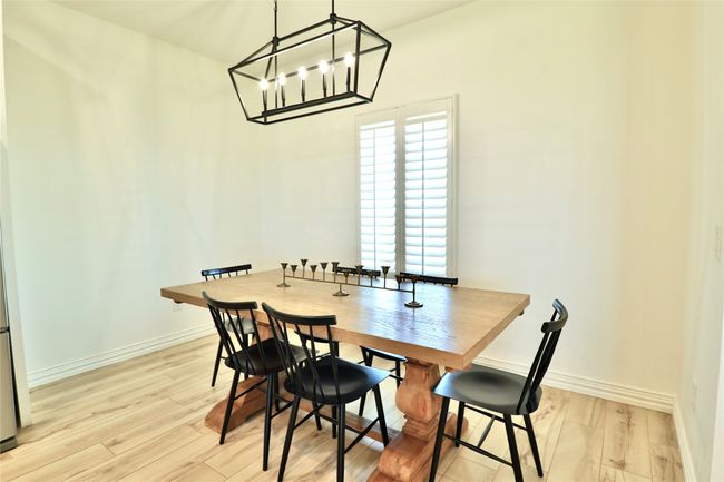 Dining room with baseboards, a notable chandelier, and light wood-style flooring | Image 11