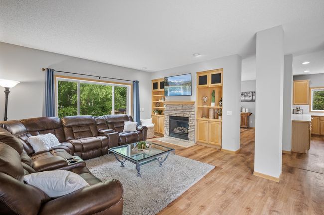 Large living room is filled with light. Features a gas fireplace, framed by built-in cabinets. | Image 9