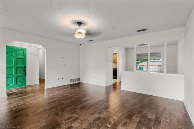 Unfurnished living room with arched walkways, wood-type flooring, ceiling fan, a textured ceiling, and baseboards | Image 8