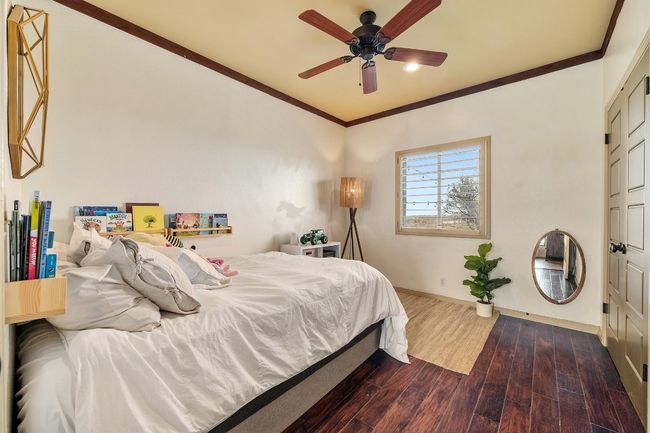 Bedroom with baseboards, dark wood-style flooring, ornamental molding, and a ceiling fan | Image 23