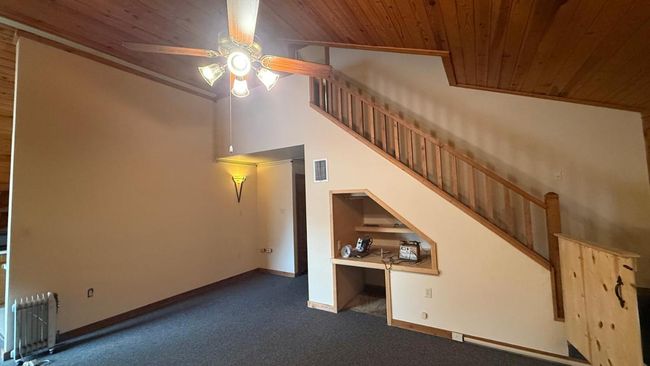Unfurnished living room with a ceiling fan, visible vents, dark carpet, and wood ceiling | Image 16