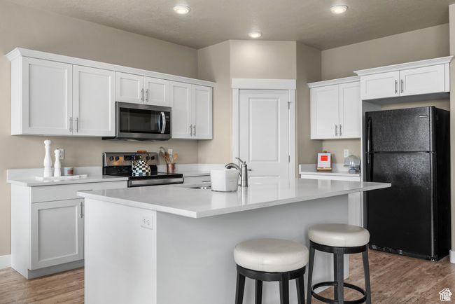 Kitchen featuring stainless steel appliances, white cabinetry, a sink, and light wood-style flooring | Image 10