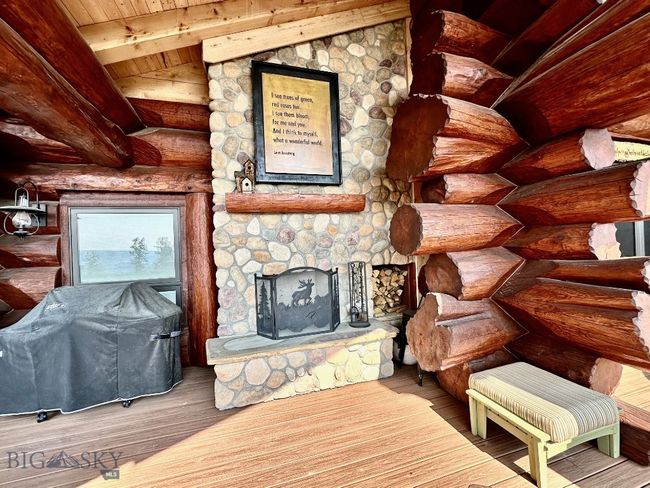 Covered deck with propane grill, exterior fireplace and log accent detail. | Image 83