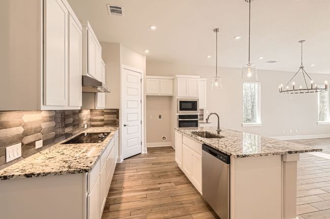 Kitchen featuring white cabinets, stainless steel appliances, light wood-style flooring, a sink, and visible vents | Image 11