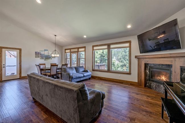 Living room featuring a premium fireplace, lofted ceiling, dark wood finished floors, recessed lighting, and a chandelier | Image 7