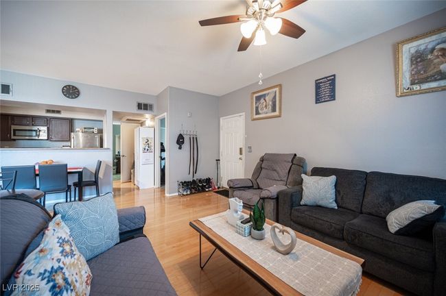 Living room with visible vents, ceiling fan, and light wood finished floors | Image 7