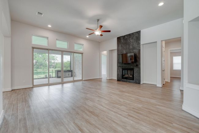 Unfurnished living room with a ceiling fan, recessed lighting, healthy amount of natural light, light wood-style flooring, and a fireplace | Image 6