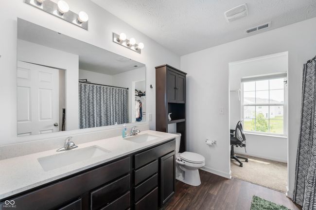 bathroom featuring double vanity and a walk in closet. | Image 12